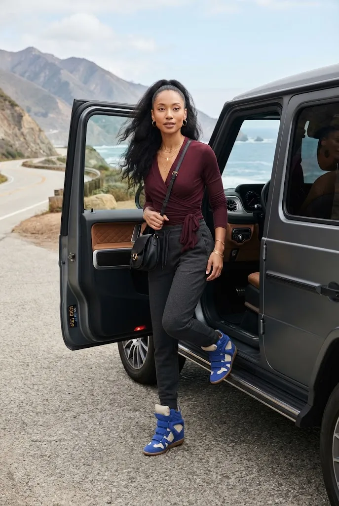 Woman in joggers wearing blue Isabel Marant-style wedge sneakers during a road trip