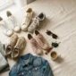 Flat lay of five easy sneakers with folded errand outfit pieces on cream linen