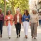 Five stylish women over 50 of different backgrounds walking together in colorful, easy weekend outfits.